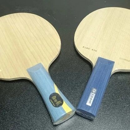 Two bare table tennis blades side by side showing wood grain and handles